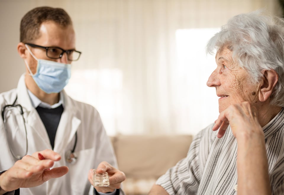 Image of man in aged care facility providing care while wearing a mask